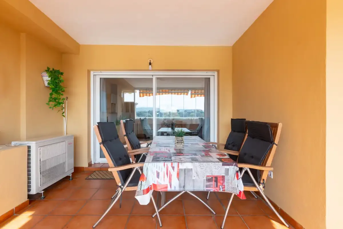 A covered terrace dining area with a table and seating.