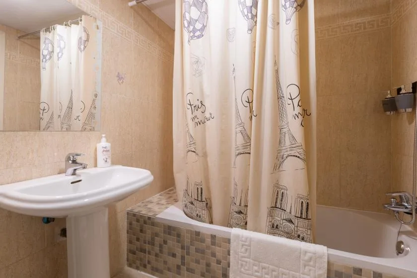 A bathroom with a pedestal sink, bathtub, and patterned shower curtain.