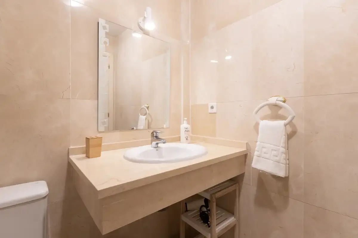 A tiled bathroom with a sink, mirror, and towel rack.