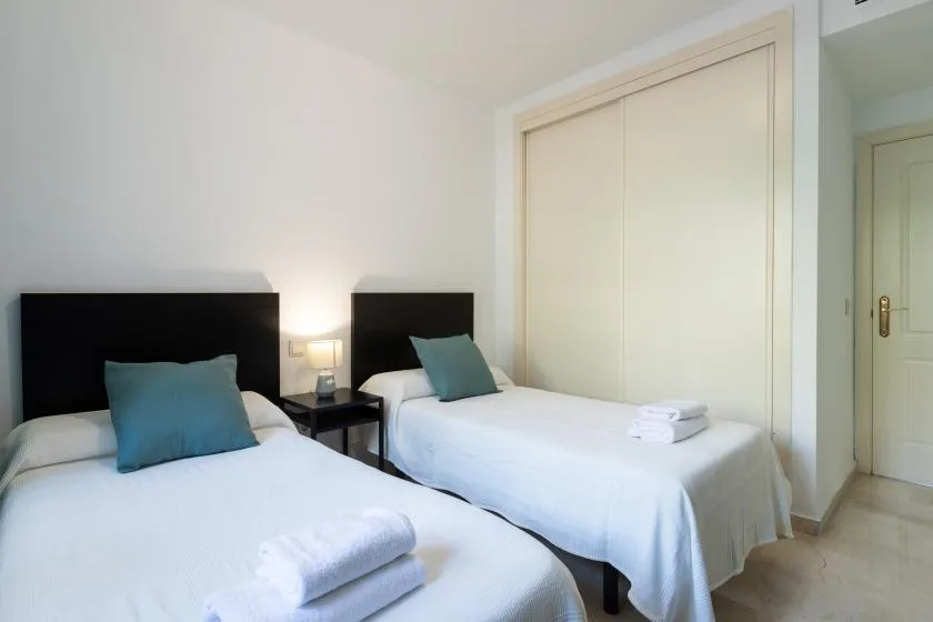 A bedroom with two single beds and folded towels.