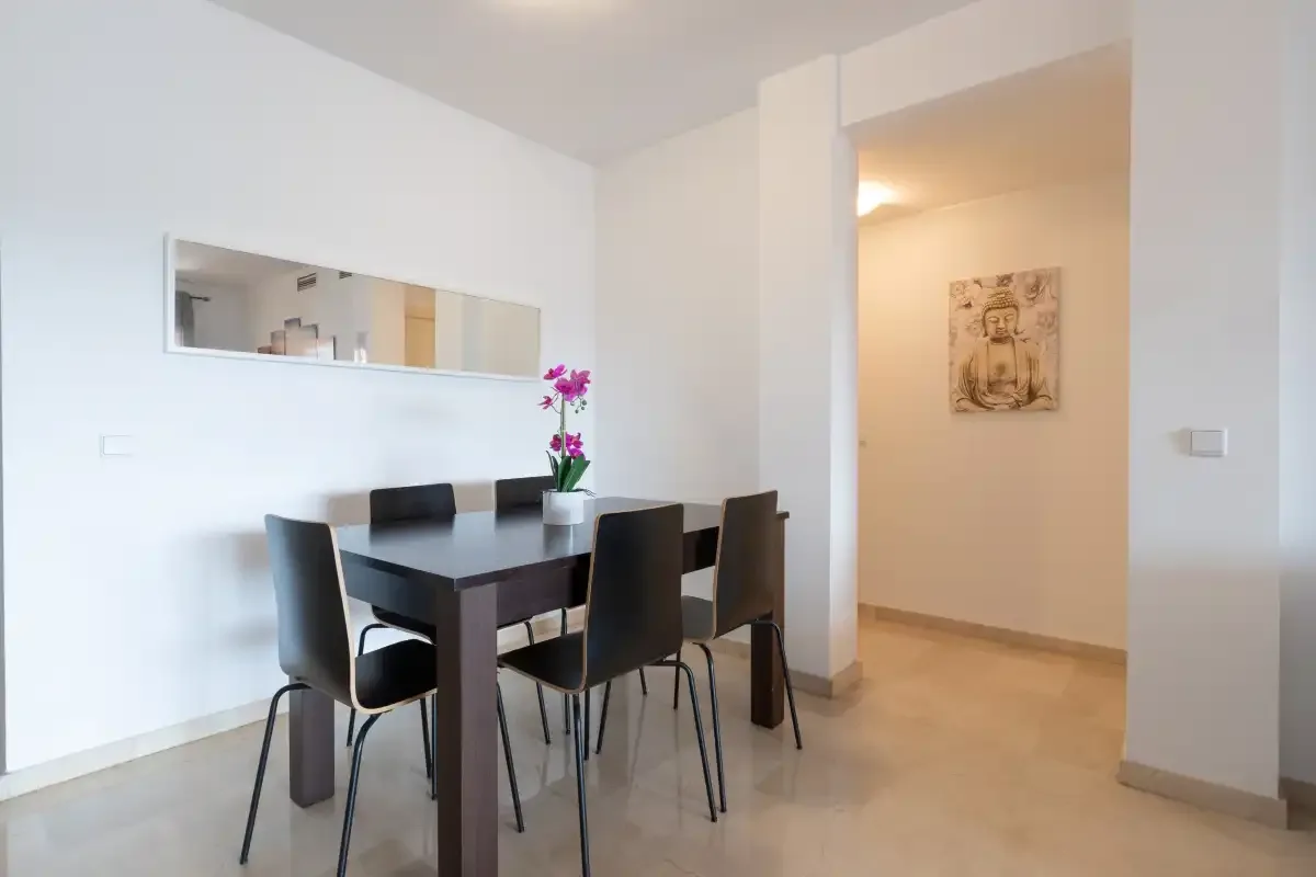 A dining area with a dark table and chairs beside a hallway.