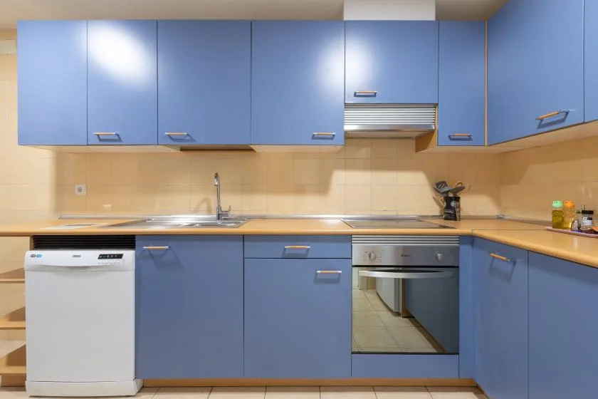 A kitchen with blue cabinets, a sink, and built-in appliances.