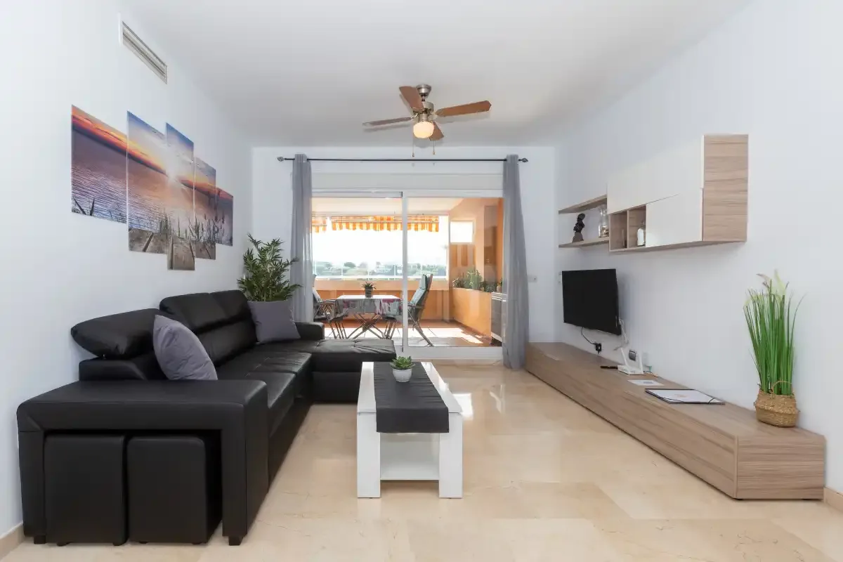 A bright living room with seating, a coffee table, and sliding glass doors.
