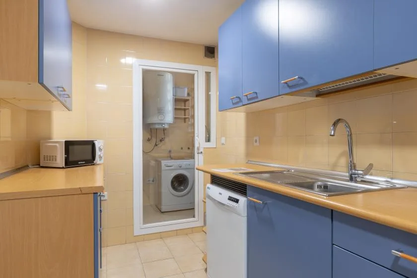 A compact kitchen with blue cabinets, a countertop, and a stainless steel sink.