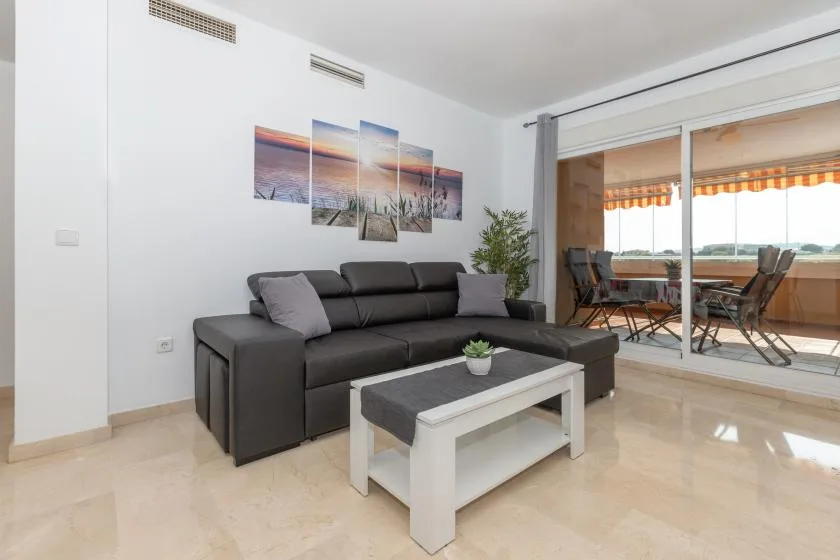A living room with dark seating and a coffee table beside glass doors to a dining area.