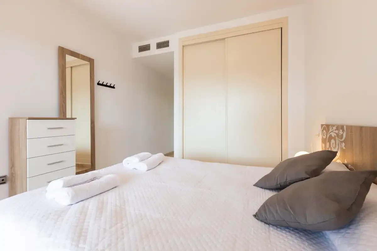 A bedroom with a neatly made bed and a wardrobe.