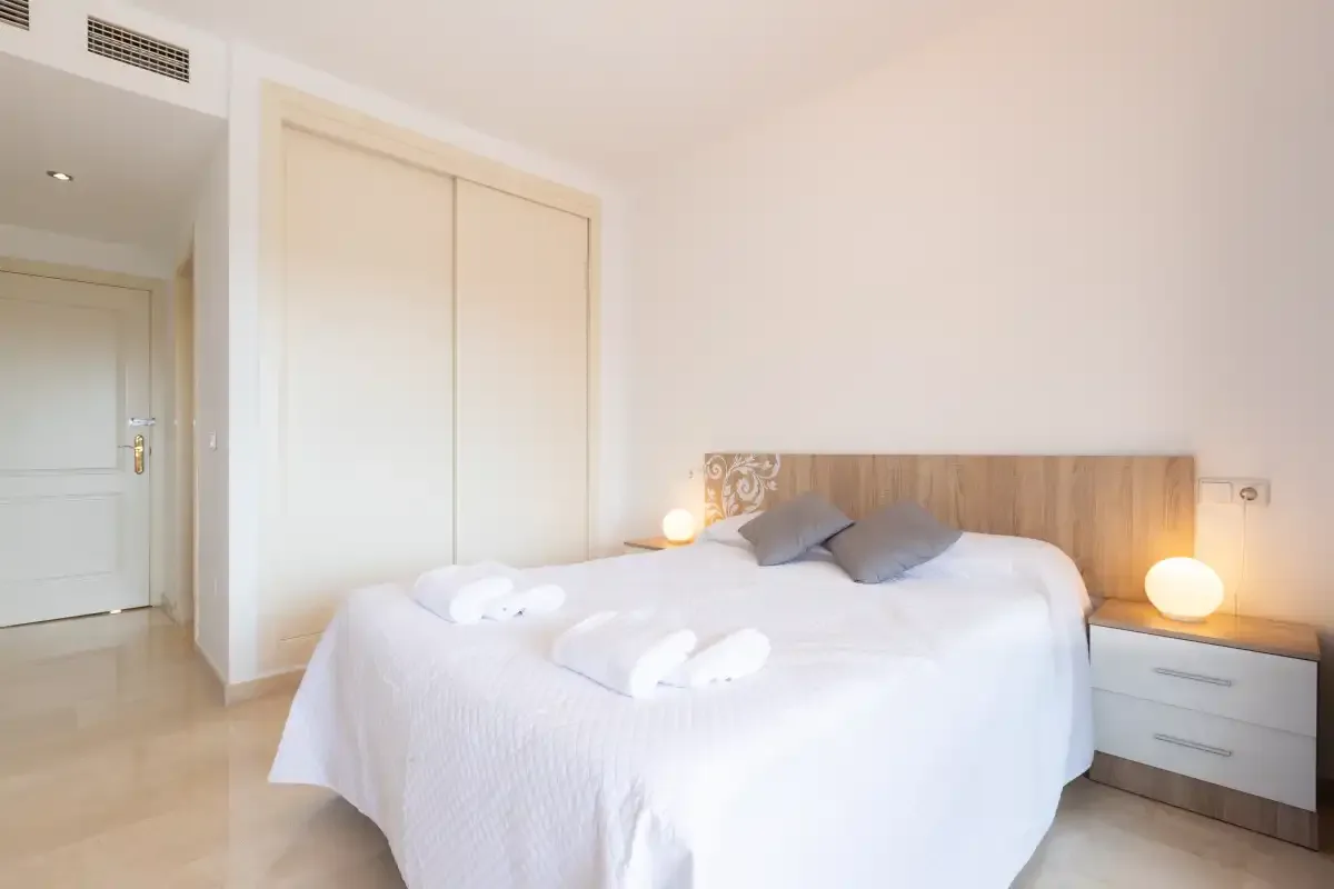 A bright bedroom with a double bed and bedside table.