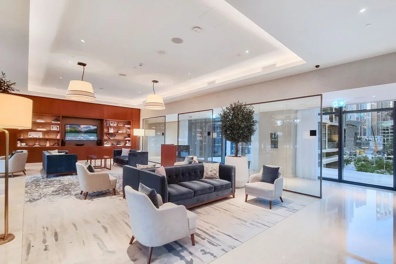 A bright lounge with seating arranged around a low table beside glass walls.