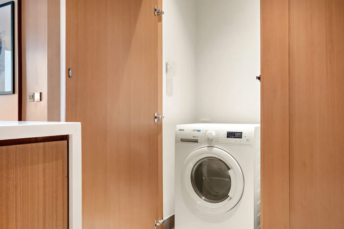 A laundry area with a front-loading washing machine between wooden doors.