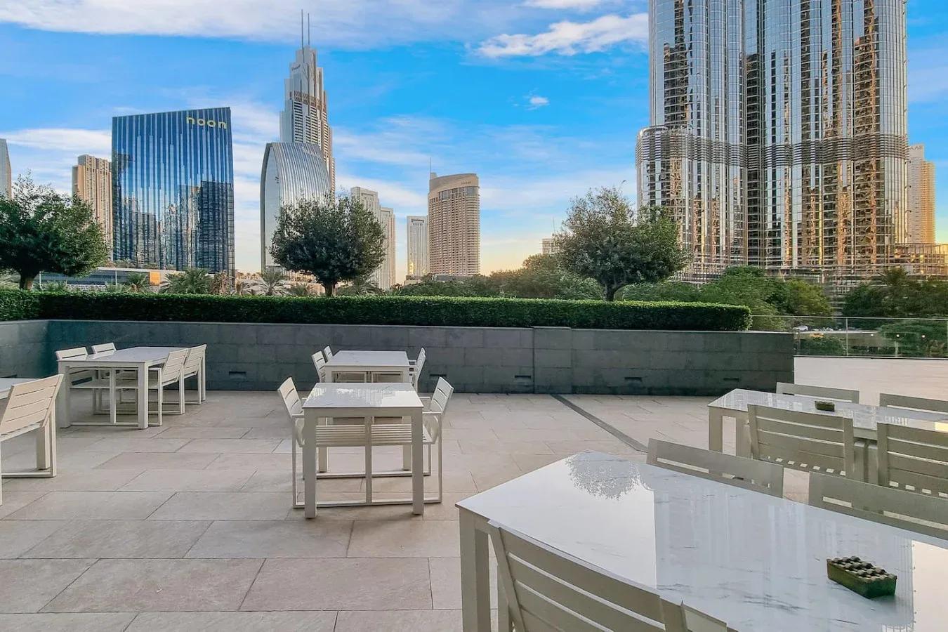 An outdoor terrace with tables and seating overlooks a city skyline.
