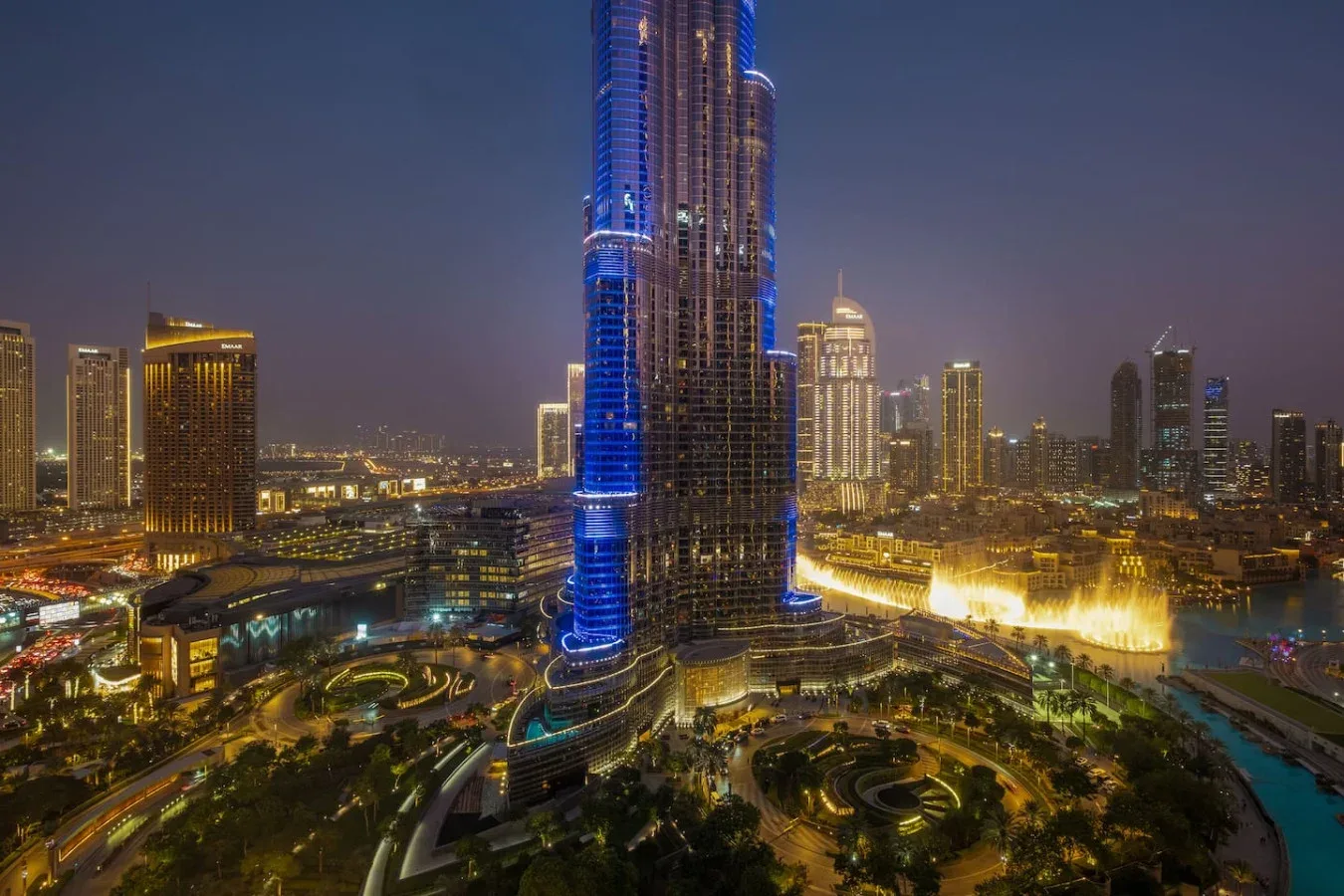 Nighttime city skyline with a brightly illuminated skyscraper and surrounding buildings.