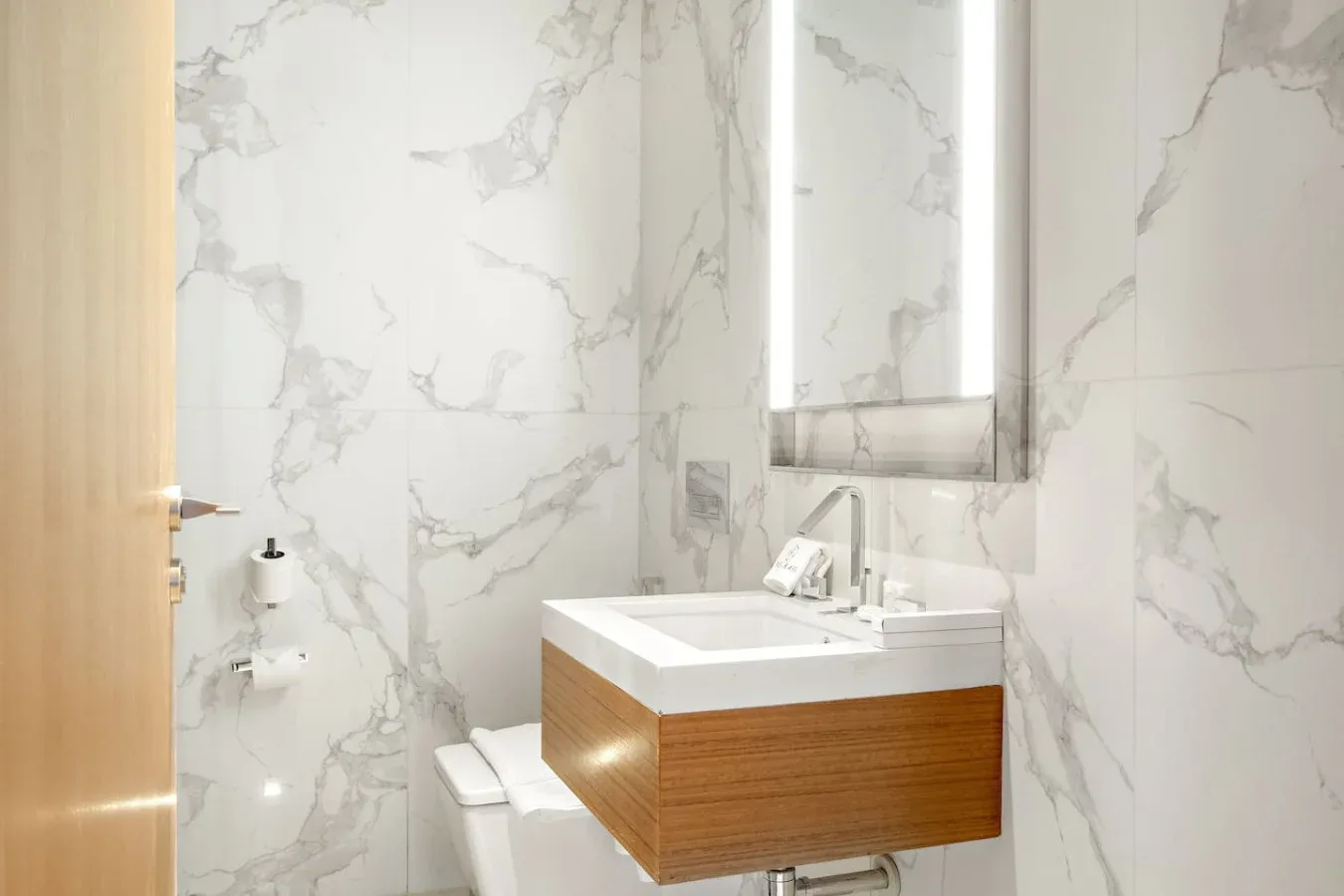 A bathroom with a wall-mounted sink and marble-patterned walls.