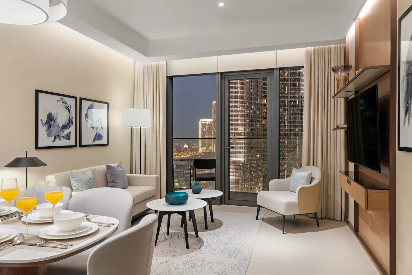 A modern living room with seating, a coffee table, and a city view through glass doors.