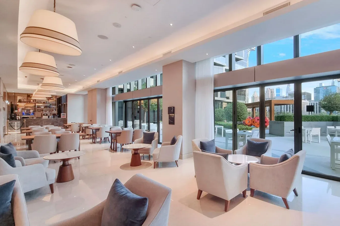 A bright lounge with cushioned seating and large windows overlooking a terrace.