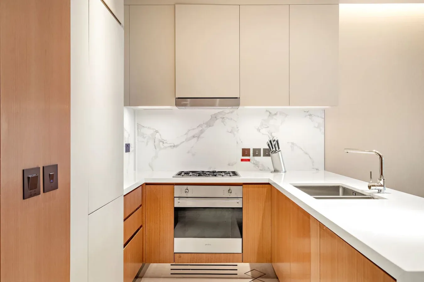 A modern kitchen with wood cabinetry, a cooktop, and a sink.