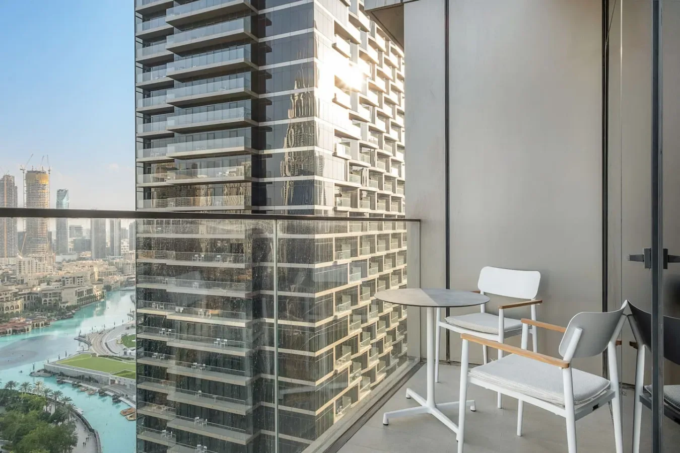 A balcony seating area overlooks nearby high-rise buildings and a waterway.