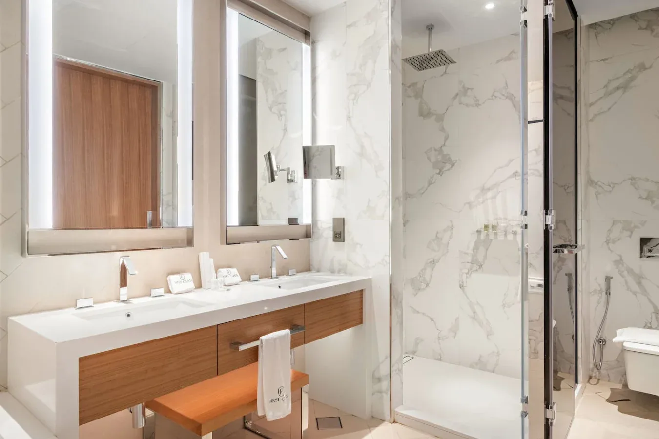 A modern bathroom with a long vanity beside a glass-enclosed shower.