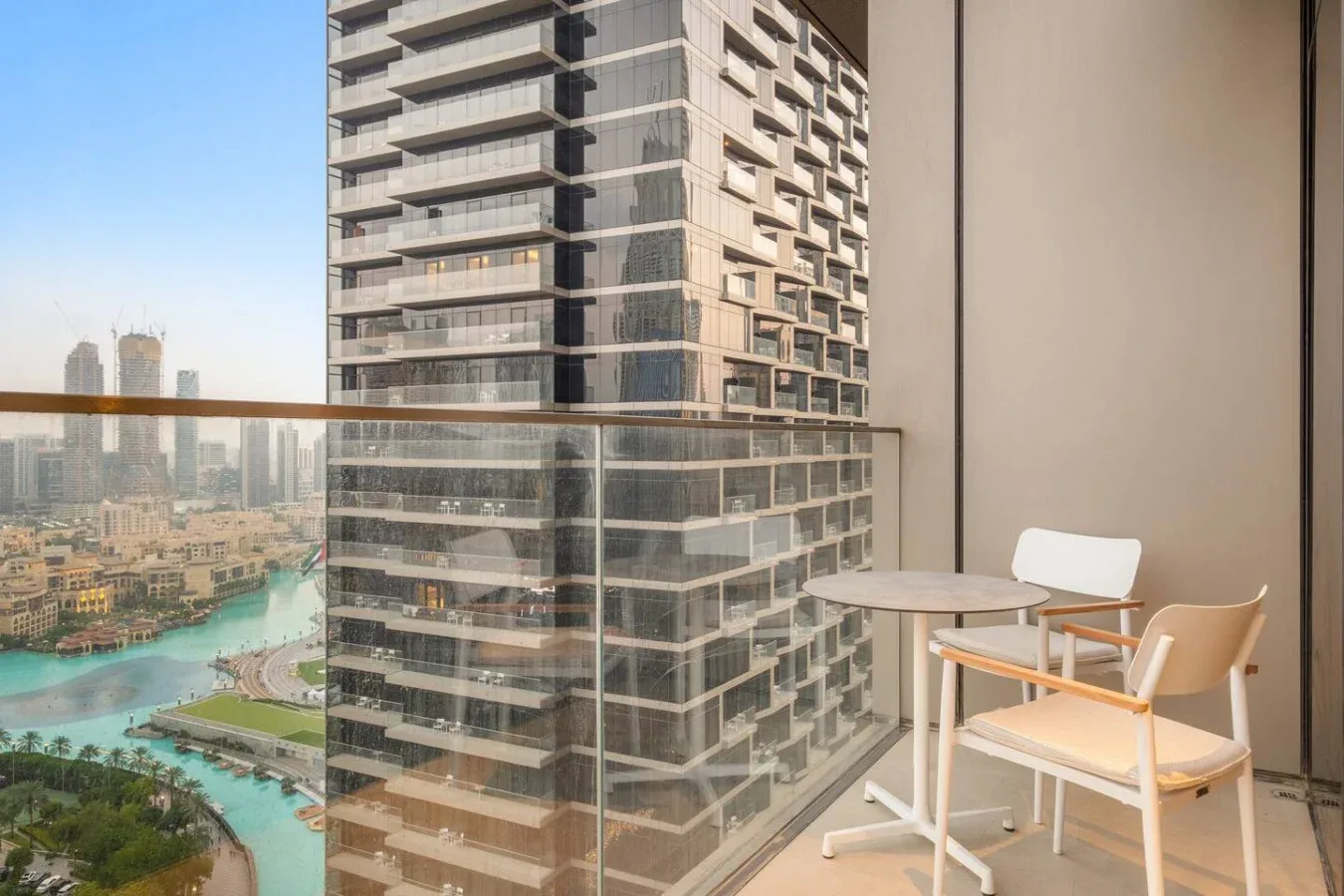 A balcony seating area overlooks nearby high-rise buildings and a curving waterway.