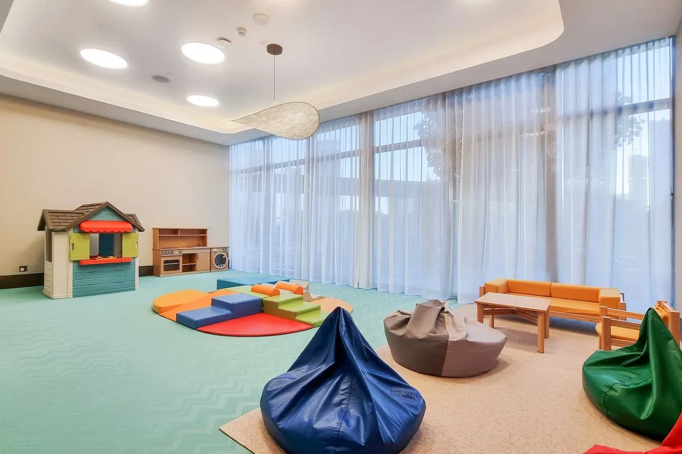 A bright playroom with colorful floor cushions and a small playhouse.