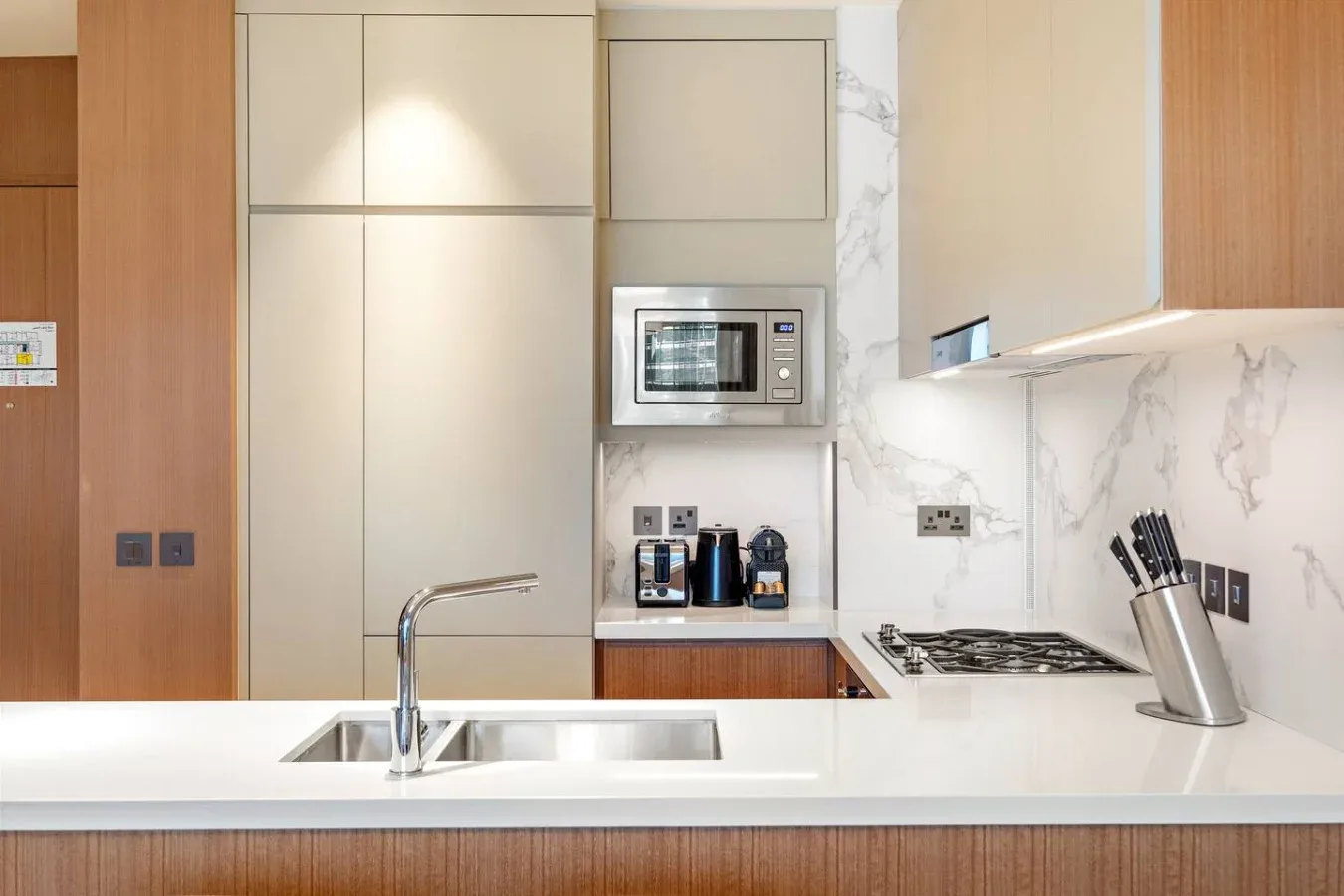 A modern kitchen with a white island, cooktop, and built-in microwave.