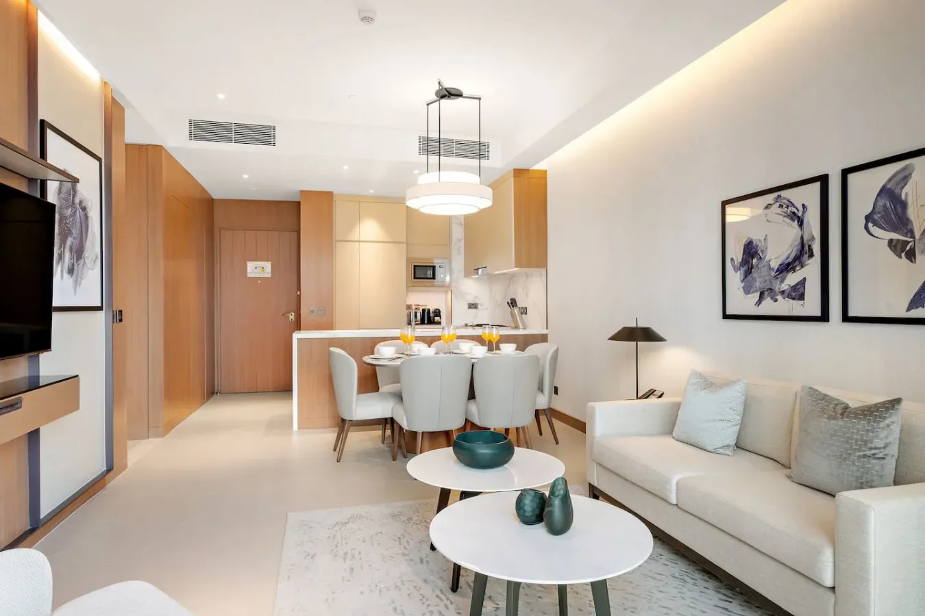 A bright living and dining area with a sofa, dining table, and open kitchen.