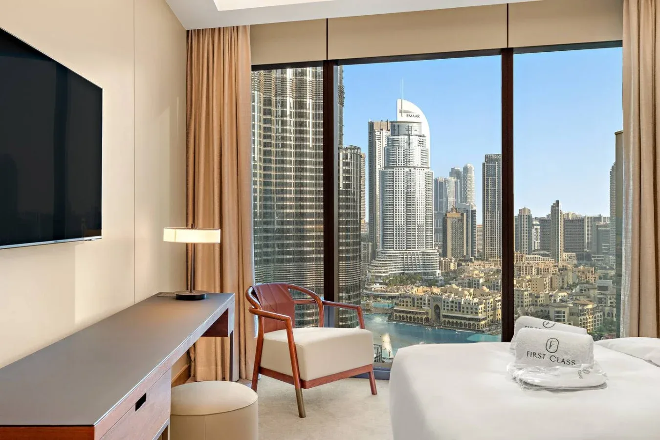 A bedroom with a bed and a large window overlooking city buildings.