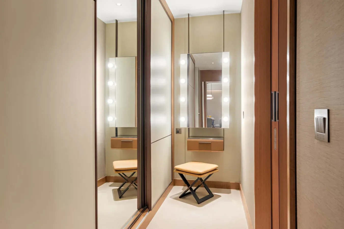 A dressing area with mirrored wardrobe doors and a small bench.