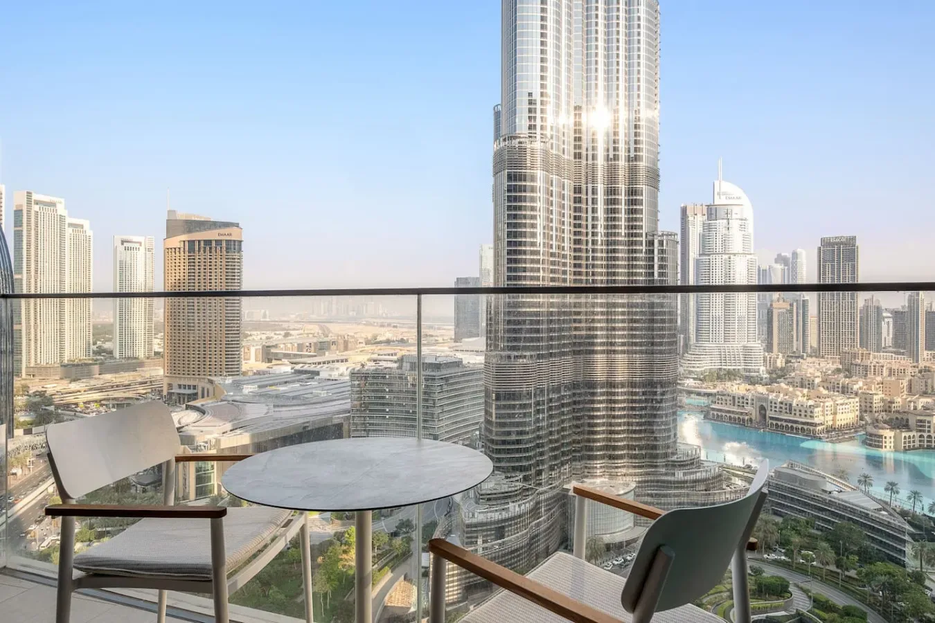 A balcony seating area overlooks a city skyline and a curving waterfront.