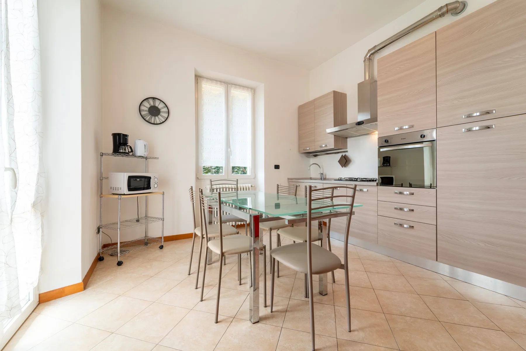 A bright kitchen and dining area with a glass table and built-in appliances.