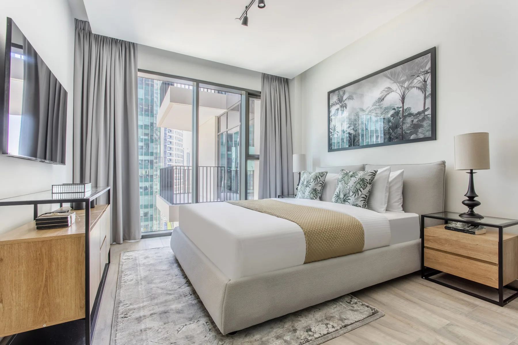Un dormitorio luminoso con una cama bien tendida y puertas corredizas de vidrio hacia un balcón.