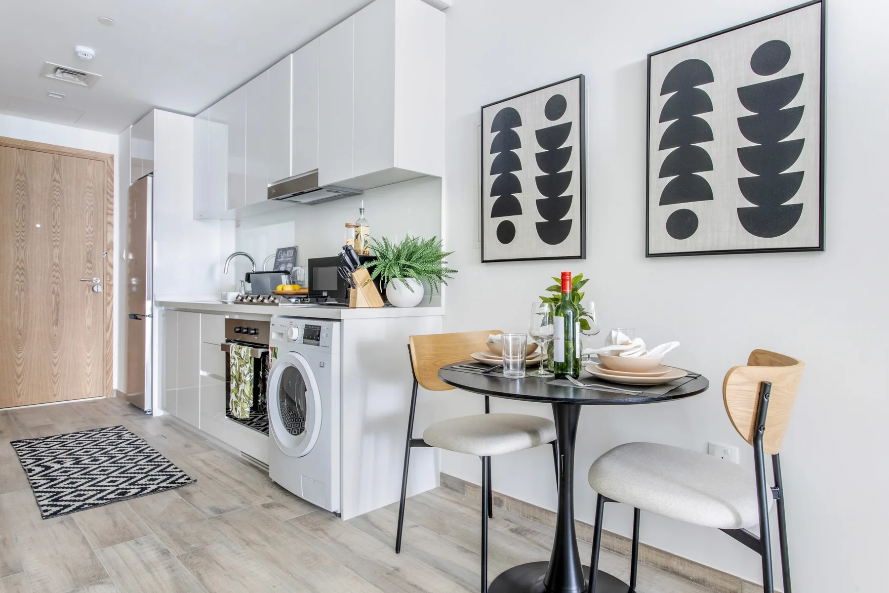 Una cocina luminosa con comedor, una mesa pequeña y láminas enmarcadas.