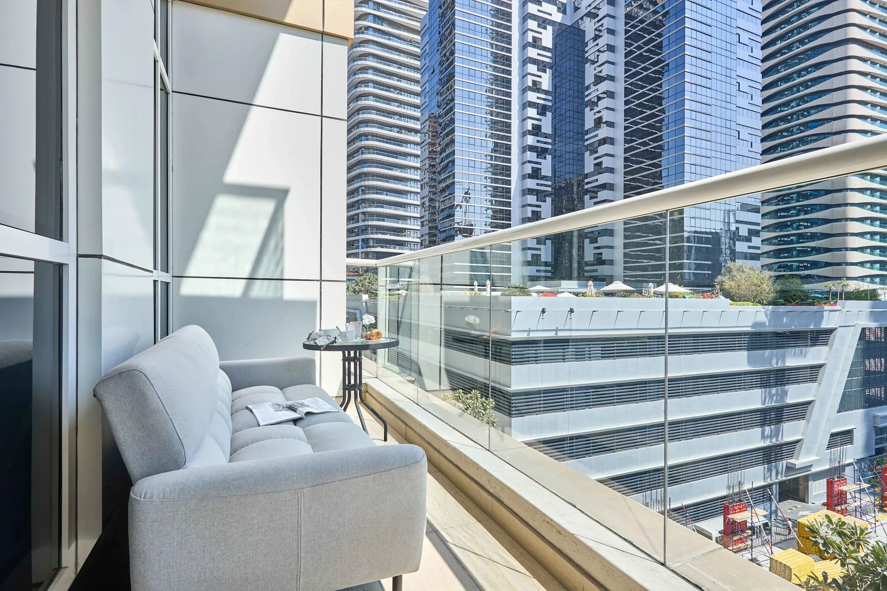 Una zona de estar en un balcón da a edificios altos cercanos.