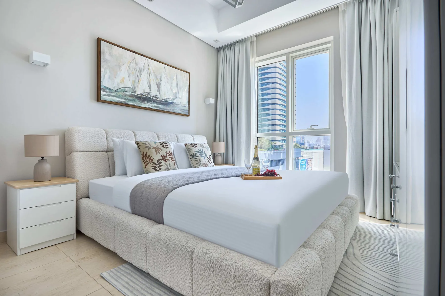 Un dormitorio luminoso cuenta con una cama grande junto a una ventana de suelo a techo.