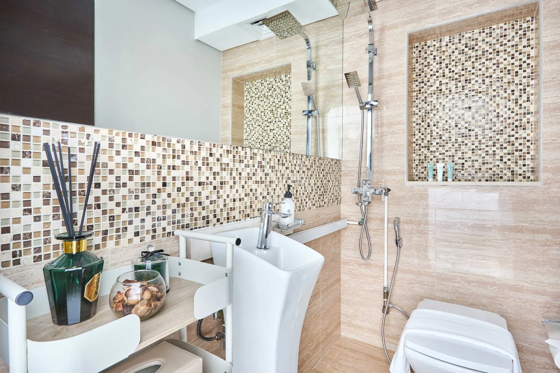 Un baño con azulejos, lavabo, accesorios de ducha en la pared e inodoro.