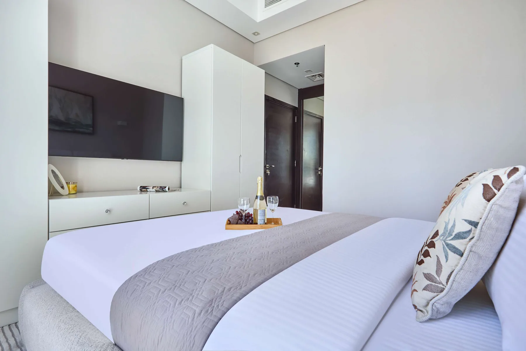 Un dormitorio con una cama bien tendida y un televisor montado en la pared.