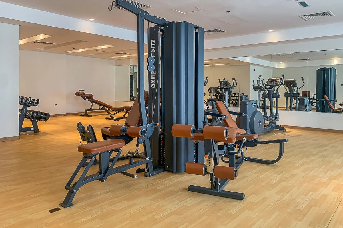 Un gimnasio con máquinas de pesas, bancos y equipo de ejercicio.