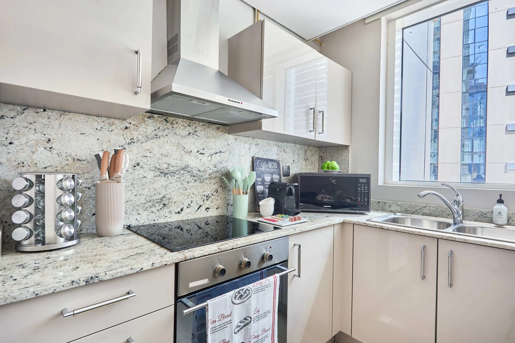 Una cocina luminosa con placa de cocción, horno y fregadero junto a una ventana grande.