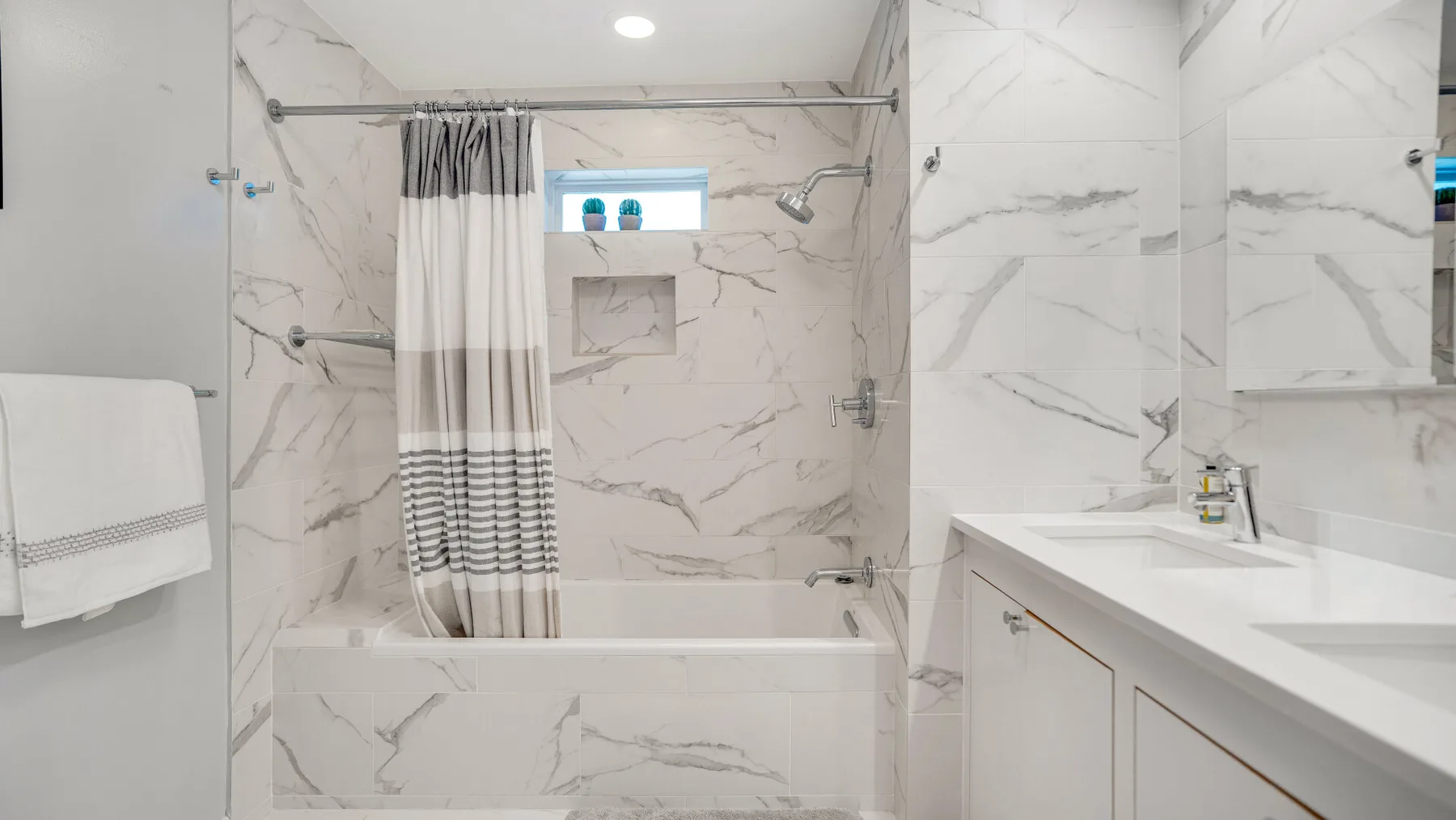 Un baño luminoso con bañera, cortina de ducha y lavabo con mueble.