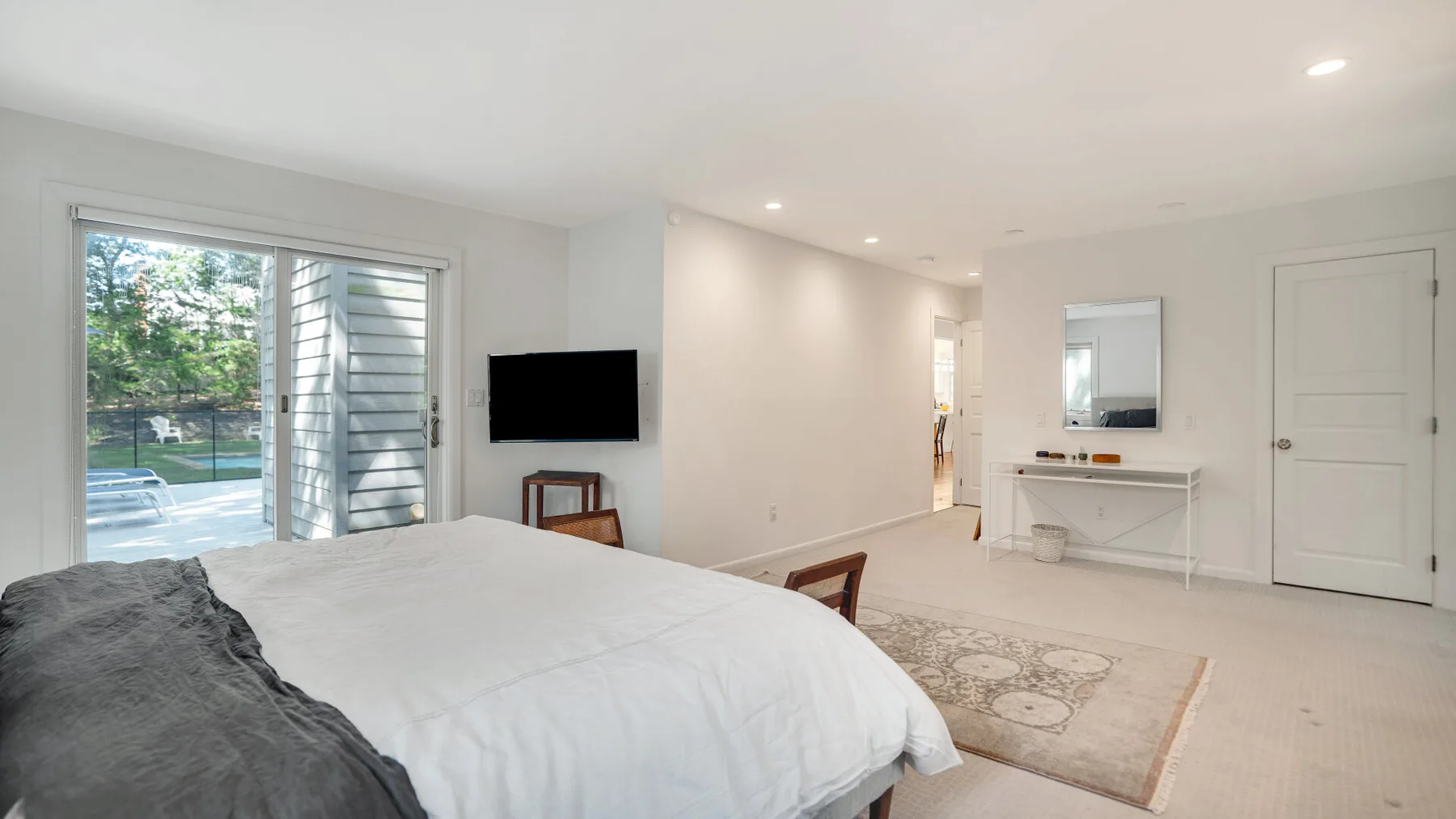 Un dormitorio luminoso con una cama grande junto a puertas corredizas de vidrio.