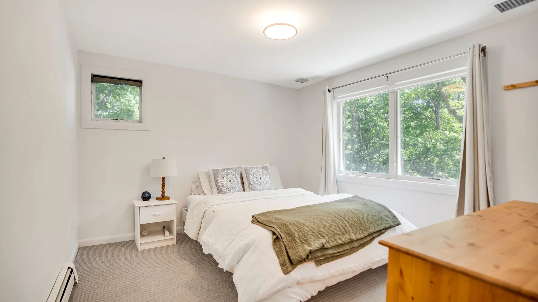 Un dormitorio luminoso con una cama, una mesita de noche y una ventana grande.
