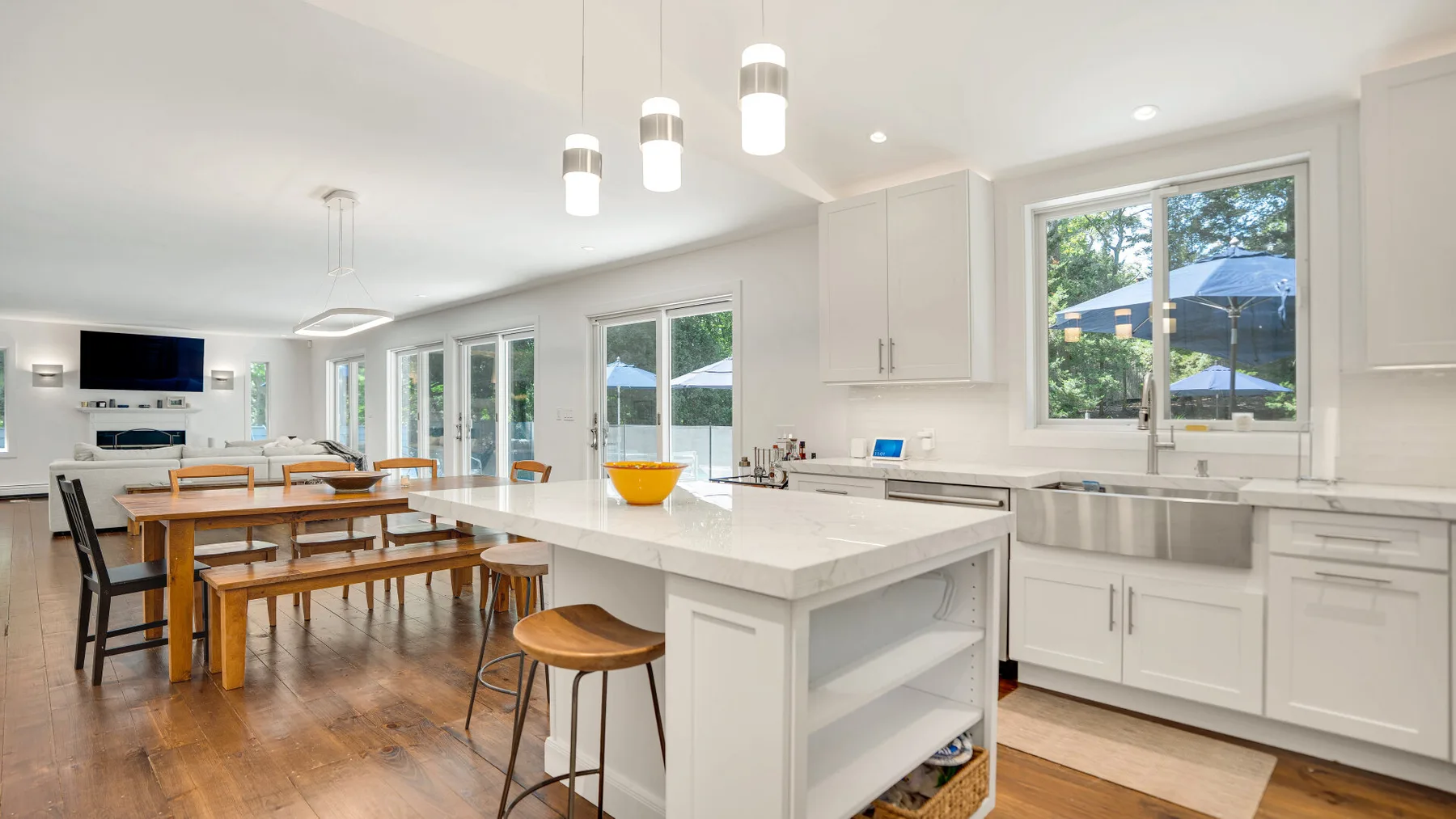 Una luminosa cocina abierta con comedor, una isla larga y una mesa de madera.