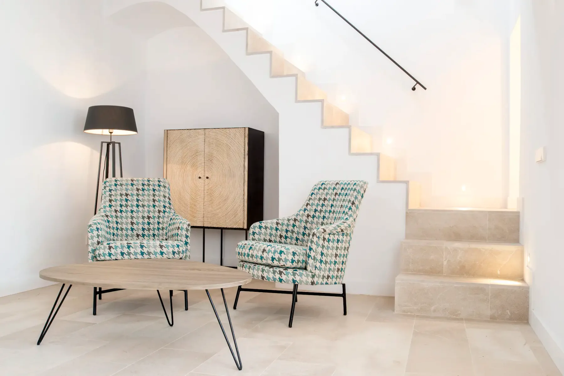 A bright living area with patterned seating beneath a staircase.