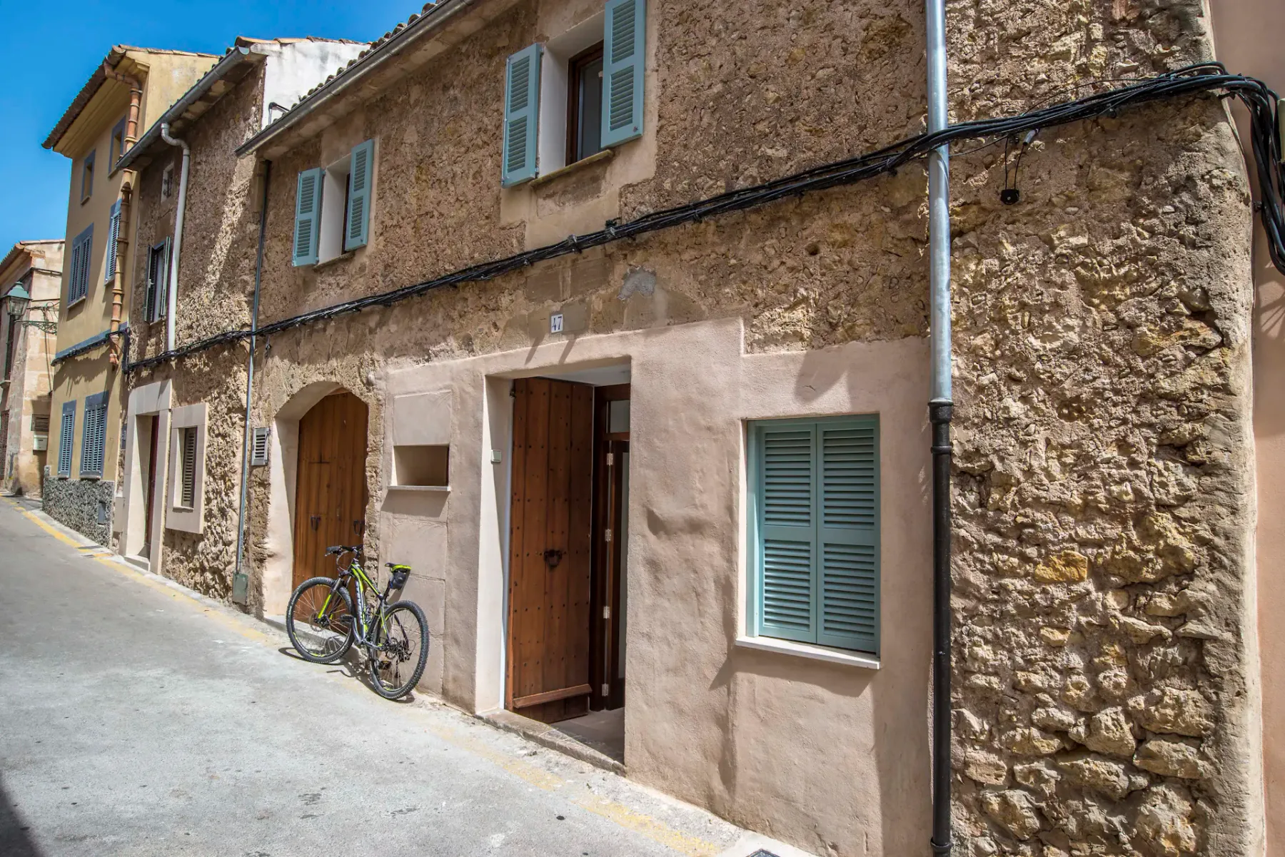 Una calle estrecha bordeada de fachadas de piedra, ventanas con contraventanas y puertas de madera.