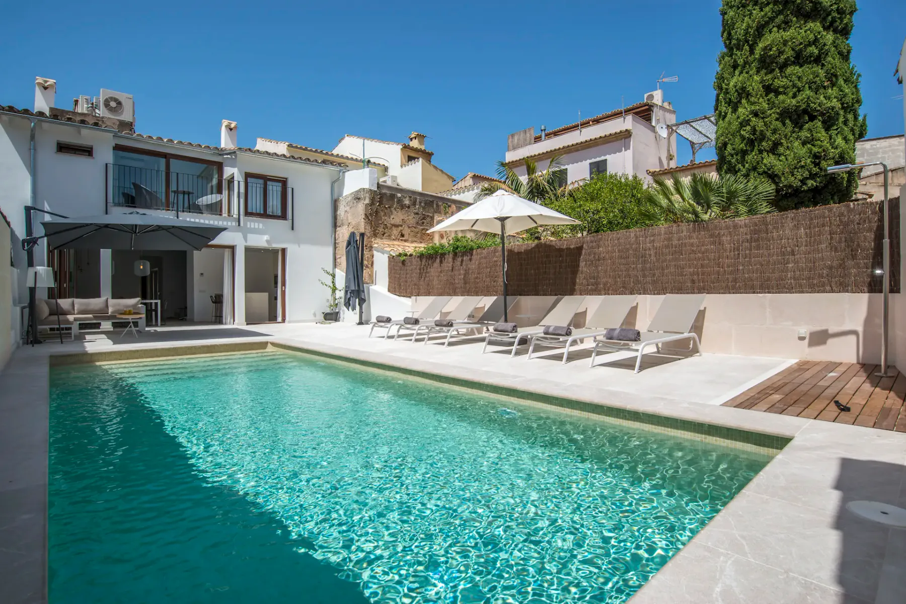 Una piscina y tumbonas ocupan un patio exterior soleado.