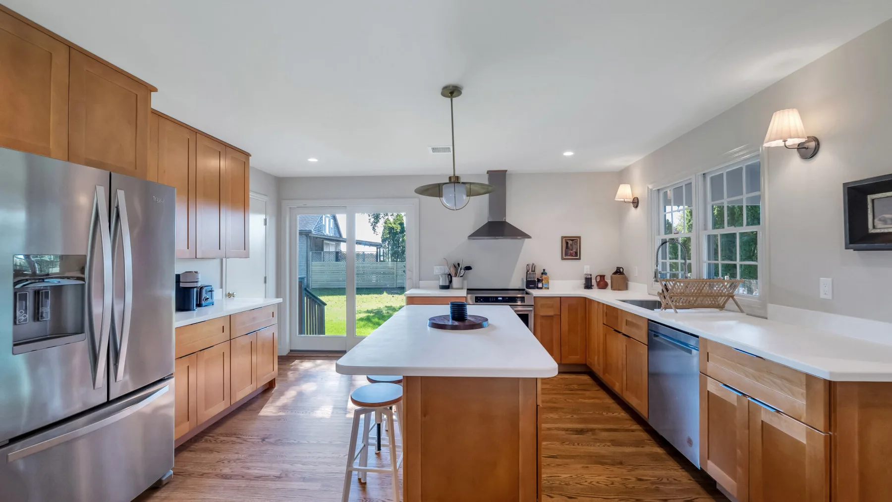 A bright kitchen with wooden cabinets, a central island, and glass doors opening to a patio.