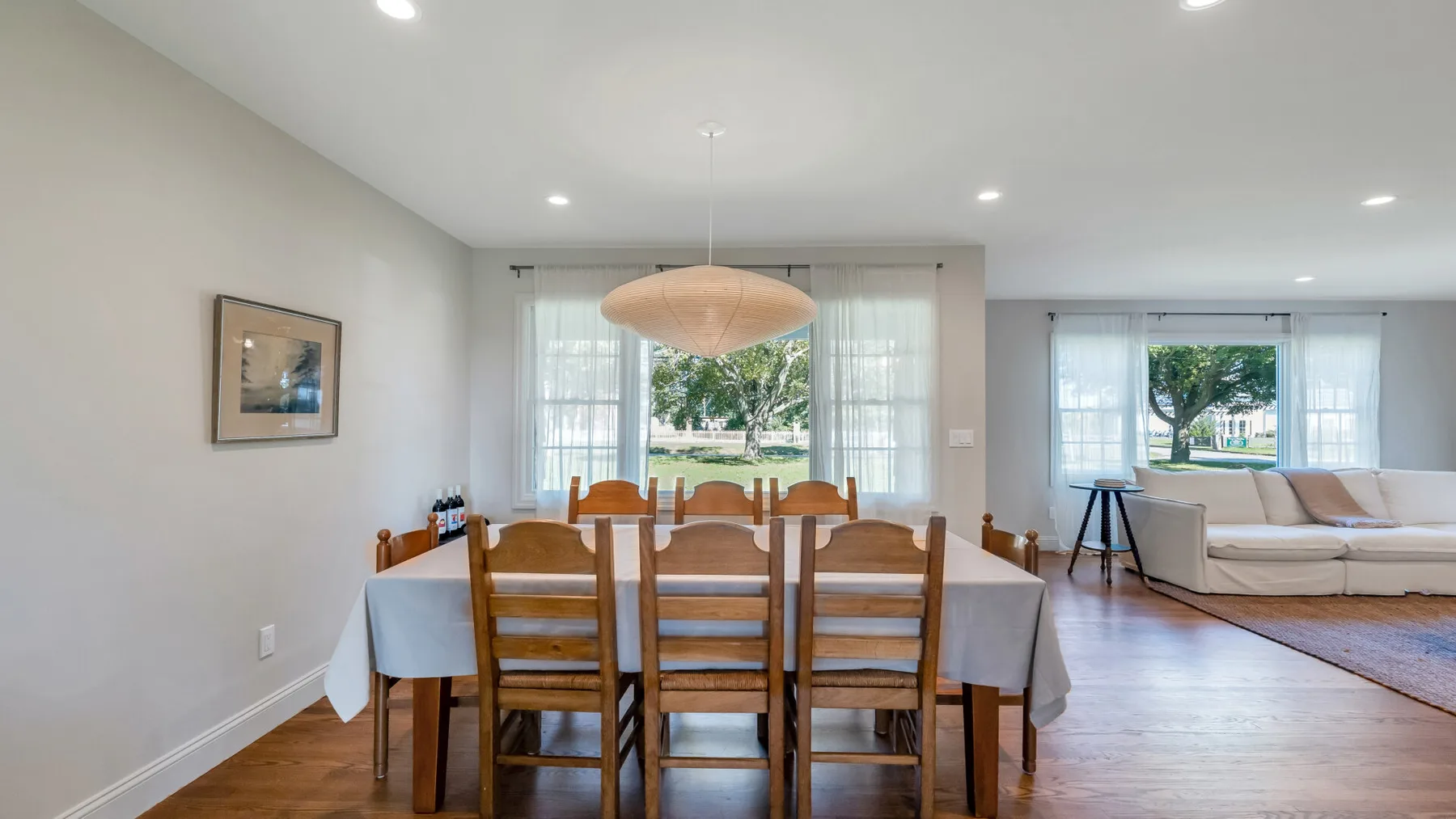 A dining area with a wooden table and chairs beside a bright living room.