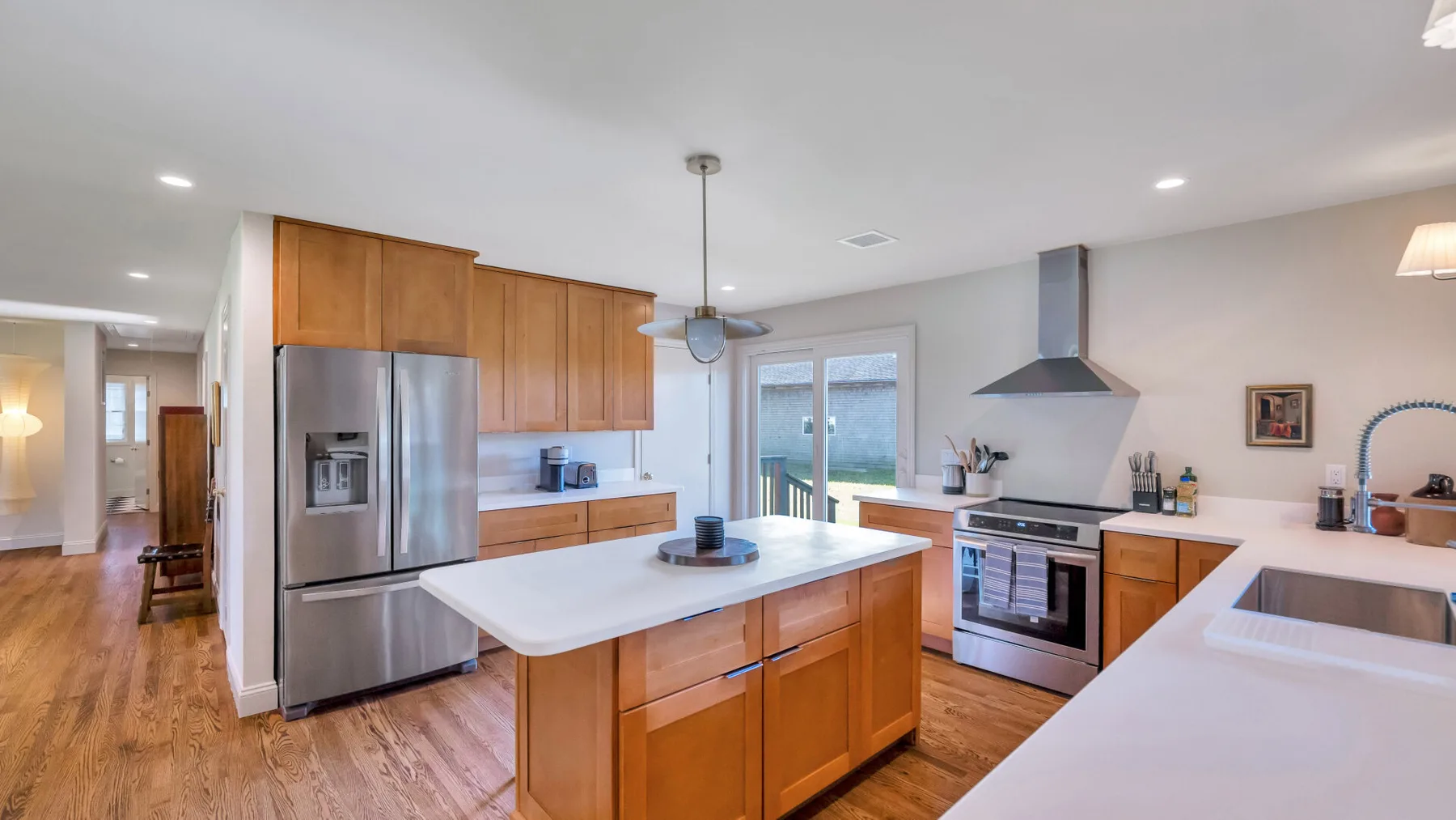 A bright kitchen with wooden cabinets, stainless steel appliances, and a central island.
