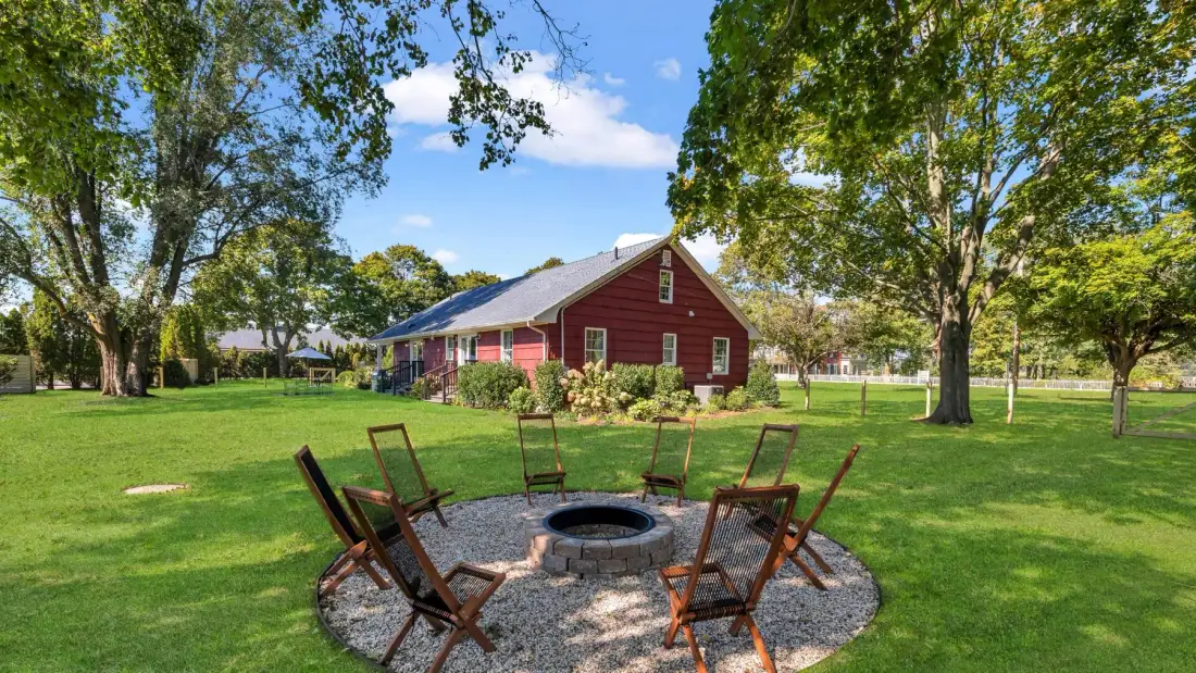 A grassy outdoor area has a circular fire pit surrounded by seating.