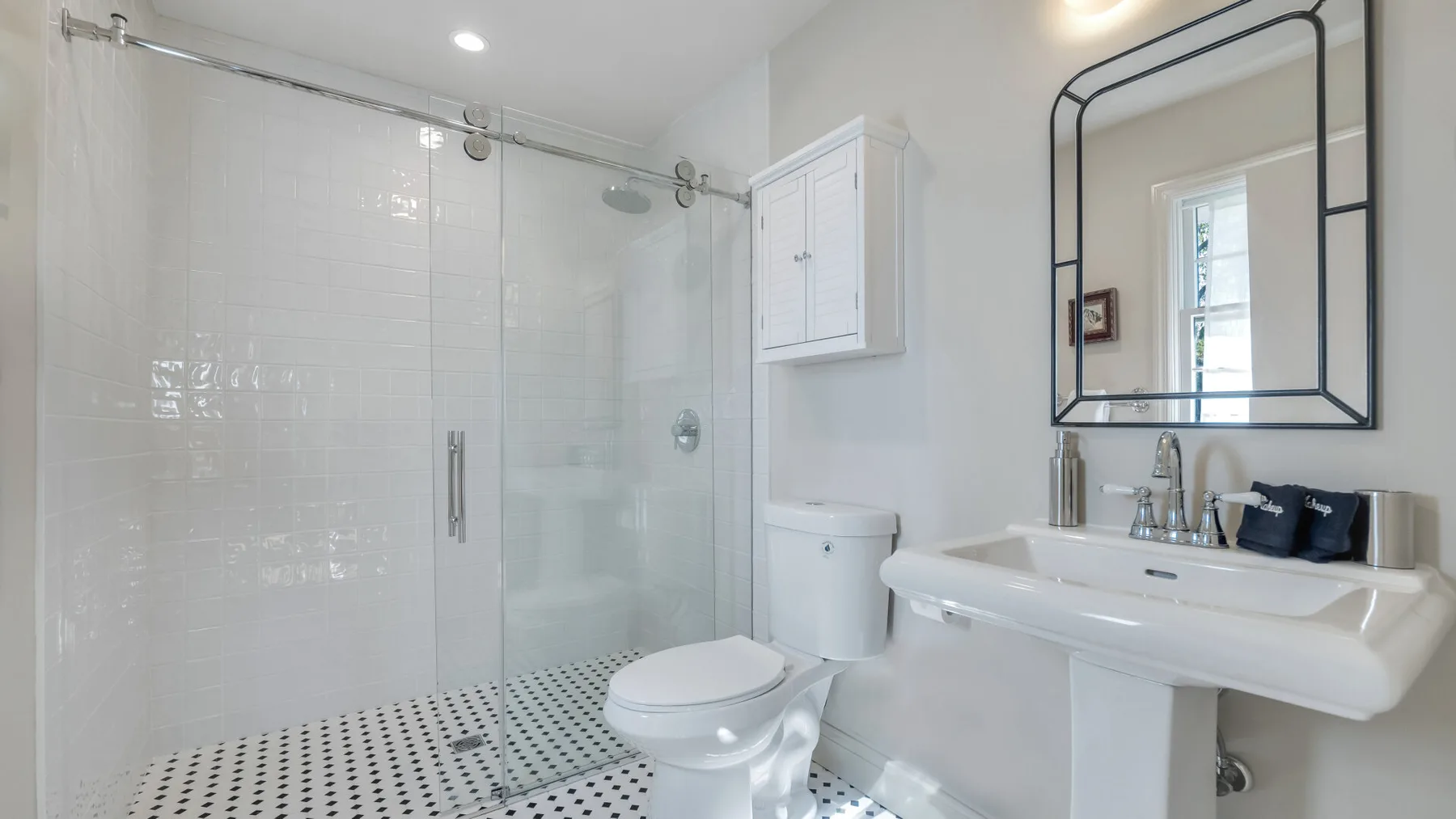 A bright bathroom with a glass shower, toilet, and wall-mounted sink.