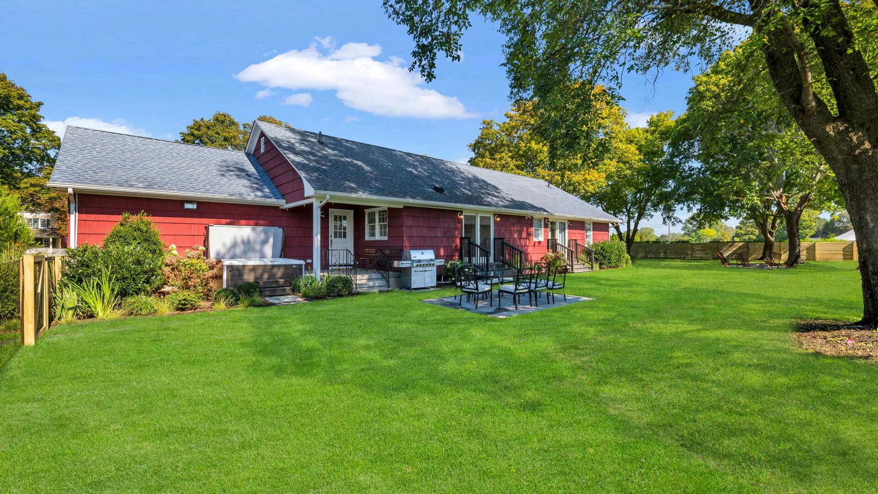 A red building sits beside a broad green lawn with outdoor picnic tables.